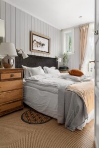 A bedroom with a bed, dresser and mirror